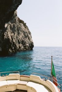 Back of a gozzo boat with crystal sea water and rock cave