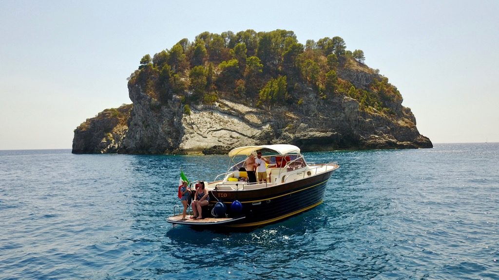 Modern gozzo boat with a rocky island on the sea