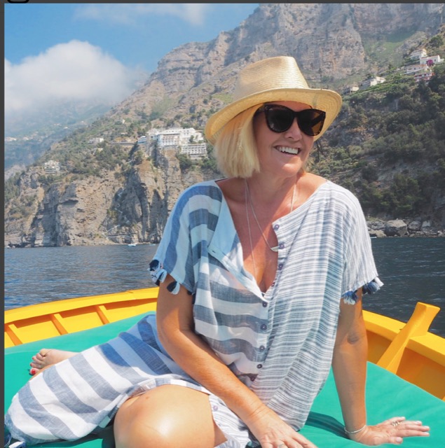 A blonde woman with hat and sunglasses on the boat