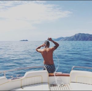 A boy taking a fresh shower on the back of the boat near the sea