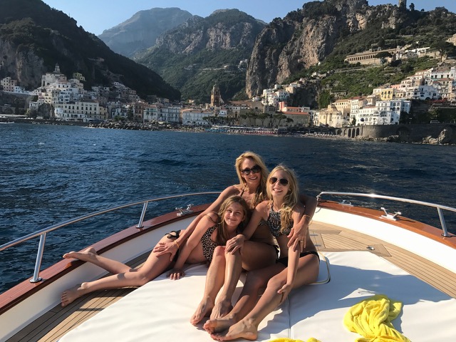 A mothers with two daughters on the front of the boat near Positano