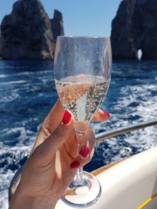 Prosecco glass in the hand with red nails on the boat in the sea